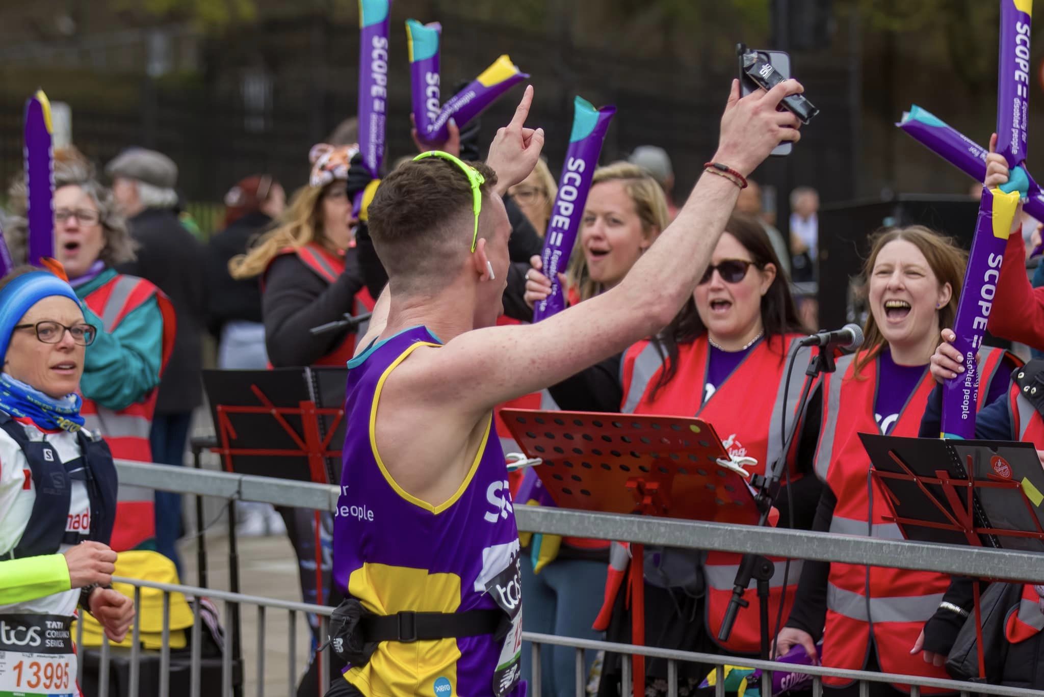 Man in purple running 'Scope' vest raising hands in the air