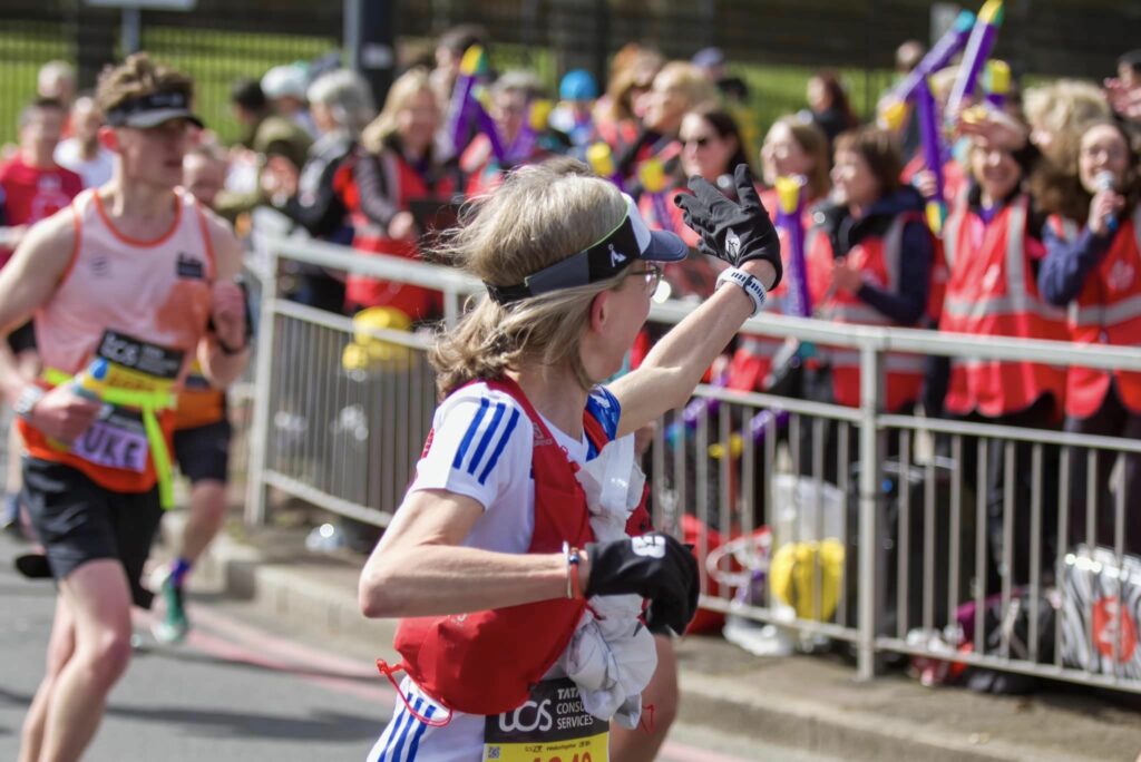 Lady with blonde hair in top waving at crowd